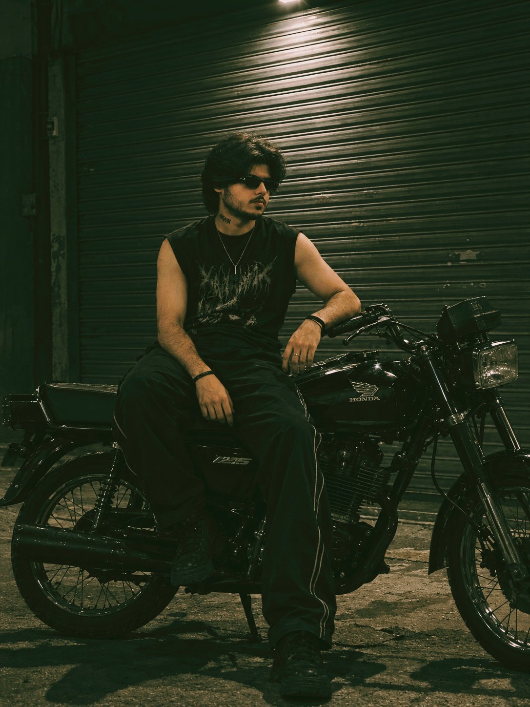 MEHAR-OG sitting on a black Honda 125 motorcycle at night