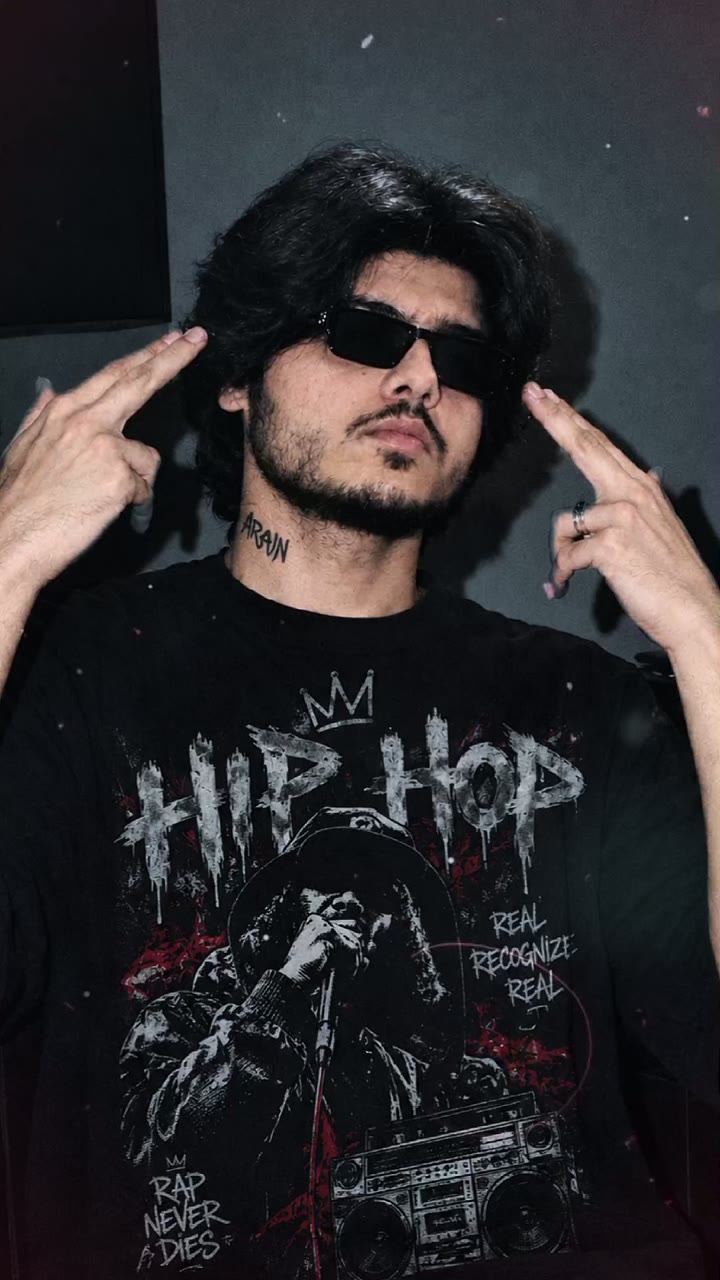 MEHAR-OG in black sunglasses and a black hip-hop graphic t-shirt, fingers pointed at his temples